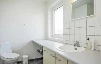 a white bathroom with a toilet and a sink at Nice Home In Blokhus With Sauna in Blokhus