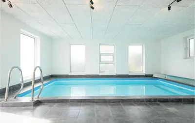 a swimming pool in a room with windows at Nice Home In Blokhus With Sauna in Blokhus