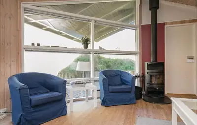 two blue chairs in a living room with a fireplace at Holiday Home Moreavej in Blokhus