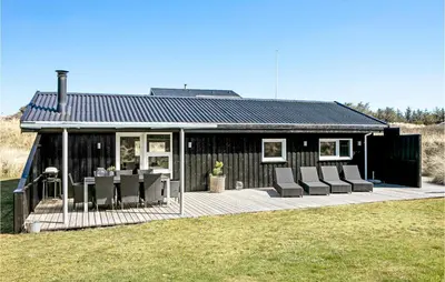 a small house with chairs and a deck at Holiday Home Tobaksvej in Blokhus