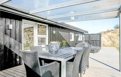 a wooden table and chairs on a deck at Holiday Home Tobaksvej in Blokhus