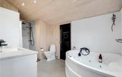 a white bathroom with a tub and a toilet at Holiday Home Tobaksvej in Blokhus