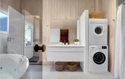 a bathroom with a washing machine and a sink at Holiday Home Tobaksvej in Blokhus