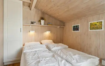 a bed in a room with a wooden wall at Pet Friendly Home In Pandrup With Sauna in Pandrup