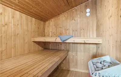 a wooden sauna with a bench and a chair at Pet Friendly Home In Pandrup With Sauna in Pandrup