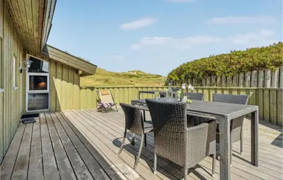 a patio with a table and chairs on a deck at Pet Friendly Home In Pandrup With Sauna in Pandrup