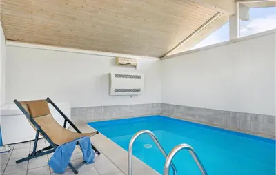 a swimming pool with a chair and a table at Pet Friendly Home In Pandrup With Sauna in Pandrup