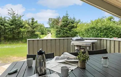 a wooden table on a patio with a tableablish at Holiday Home Østersvej Fjerritslev Xii in Fjerritslev