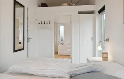 a white bedroom with a bed and a bathroom at Holiday Home Kronvildtvej Brovst Ii in Brovst