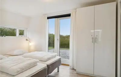 a white bedroom with two beds and a window at Holiday Home Kronvildtvej Brovst Ii in Brovst