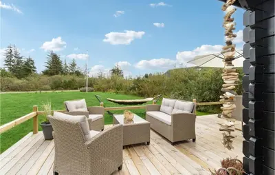 a deck with wicker chairs and a table at Holiday Home Kronvildtvej Brovst Ii in Brovst