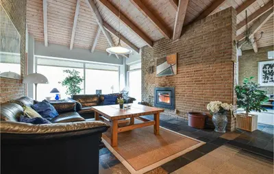 a living room with a leather couch and a fireplace at Klitborgen in Harboør