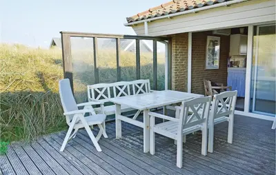 a table and chairs on a deck with a house at Klitborgen in Harboør