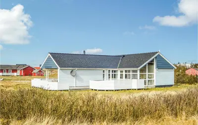 a white house with a black roof in a field at Holiday Home Themisvej Harboøre Xii in Harboør