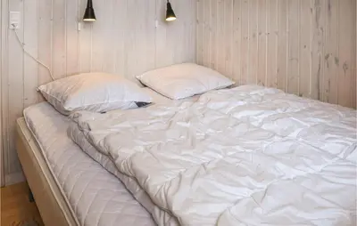 a large white bed with two pillows in a room at Holiday Home Themisvej Harboøre Xii in Harboør