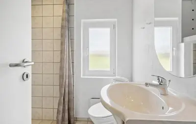 a bathroom with a sink and a toilet and a mirror at Holiday Home Vejlby Klit in Harboør