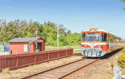 an orange train is coming down the tracks at Holiday Home Vejlby Klit in Harboør