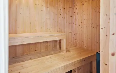 a wooden sauna with a wooden bench in it at Holiday Home Vejlby Klit in Harboør