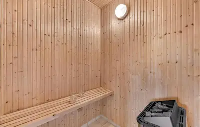 a wooden sauna with a bench and a clock at Holiday Home Klitengene Ulfborg Vi in Ulfborg