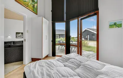 a bedroom with a large bed and a balcony at Holiday Home Klitengene Ulfborg Vi in Ulfborg