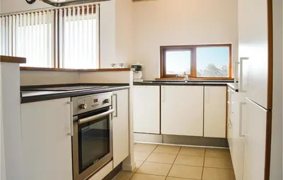 a kitchen with white cabinets and a stove top oven at Holiday Home Klitengene Xi in Ulfborg