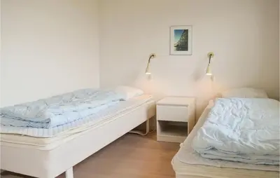 a bedroom with two beds and a night stand with a bed sidx sidx sidx sidx at Holiday Home Klitengene Xi in Ulfborg