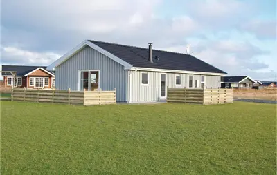 a white house with a black roof on a grass field at Holiday Home Bjergehusvej in Harboør