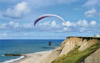 a person flying a parachute over the ocean at Holiday Home Doblervej Harboøre X in Harboør