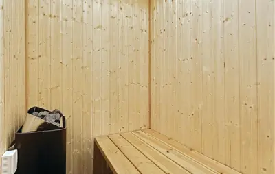a corner of a wooden sauna with a trash can at Holiday Home Doblervej Harboøre Denm in Harboør