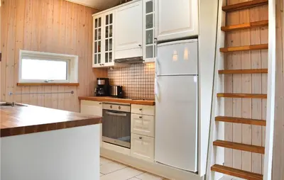 a kitchen with white cabinets and a refrigerator at Frk Lyng in Harboør