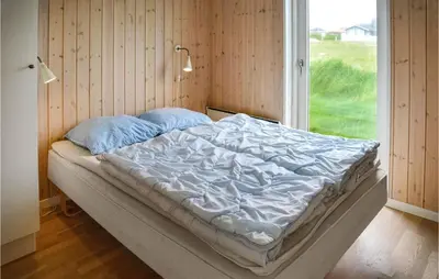 an unmade bed in a room with a window at Frk Lyng in Harboør