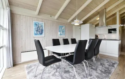 a dining room with a white table and black chairs at Holiday Home Arcticvej Harboøre Iv in Harboør