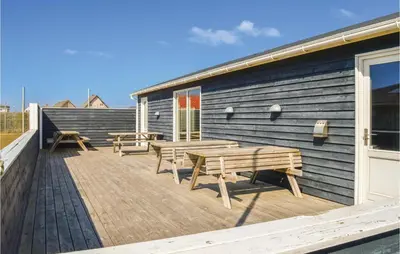a deck with benches and tables on the side of a building at Hytte 6 in Thyborøn