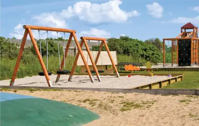a playground with a swing set in a park at Hytte 6 in Thyborøn