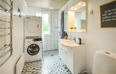 a bathroom with a washing machine and a sink at Fjordglimt in Vestervig