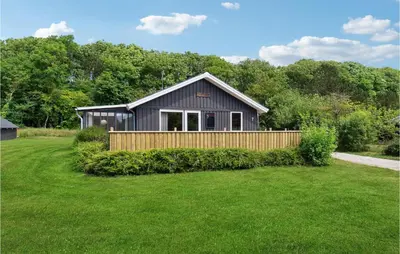 a black house with a wooden fence in a yard at Fjordglimt in Vestervig