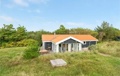 a small house with an orange roof in a field at Holiday Home Kristinesvej Xii in Thisted