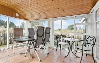 a screened in porch with tables and chairs and windows at Holiday Home Kristinesvej Xii in Thisted