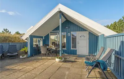a blue cottage with a table and chairs on a patio at Åbo in Thisted