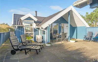 a blue house with chairs and a table on a patio at Åbo in Thisted
