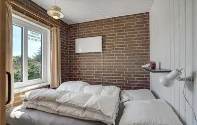 a bed in a room with a brick wall at Holiday Home Clemmessti in Thisted