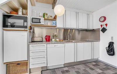 a kitchen with white cabinets and a refrigerator at Holiday Home Havnevej in Vestervig