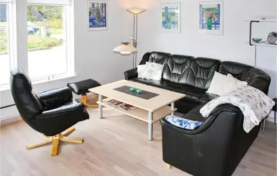 a living room with a black leather couch and a table at Holiday Home Sivsangervej Vestervig X in Vestervig