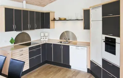 a kitchen with black cabinets and white appliances at Holiday Home Sivsangervej Vestervig X in Vestervig