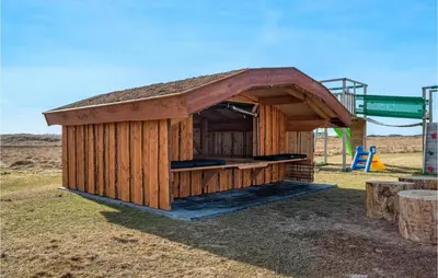 a small wooden building with a playground in a field at Amazing Home In Thisted With Sauna in Thisted