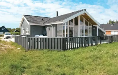 a house with a wooden fence in the grass at Holiday Home Søtungevej in Thisted