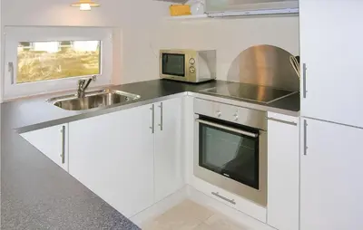 a kitchen with white cabinets and a sink and a microwave at Holiday Home Klitstien Ii in Thisted
