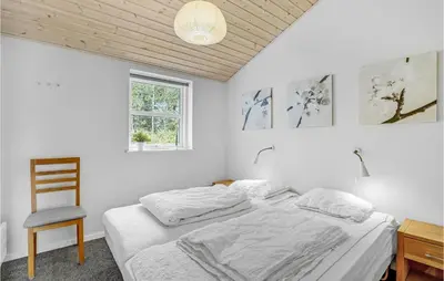 a white bedroom with a bed and a chair at Holiday Home Kristinesvej Thisted Vi in Thisted