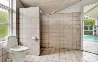 a tiled bathroom with a toilet and a window at 4 Bedroom Lovely Home In Vestervig in Vestervig