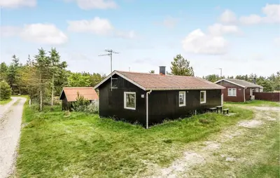a small black house on a grass field next to a dirt road at Holiday Home Mølgårdsvej Thisted in Thisted
